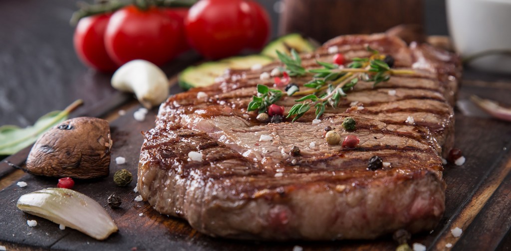Beef rump steak on black stone table, close-up.