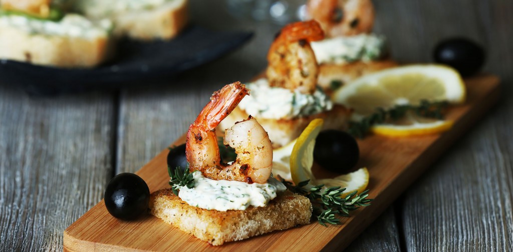 Appetizer canape with shrimp and olives on cutting board on tabl